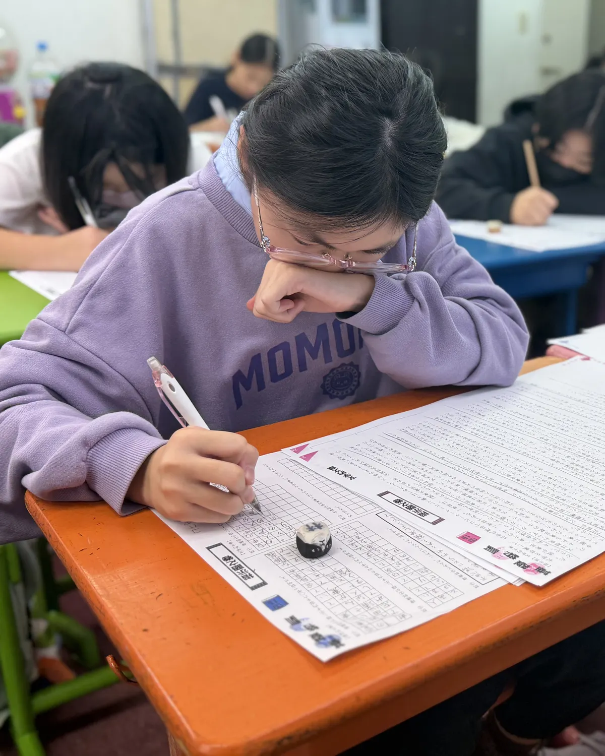 頬に手を当て、答案に向かって考え込む生徒